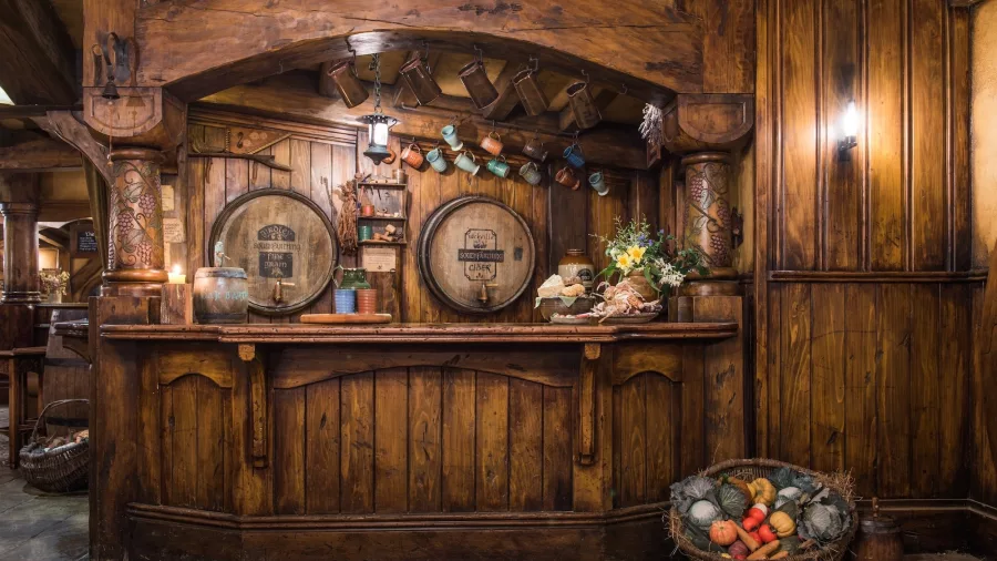 Rustic bar inside the Green Dragon Inn at Hobbiton Movie Set with wooden barrels and mugs hanging above