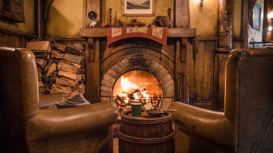 Warm fireplace and rustic seating inside the Green Dragon Inn at the Hobbiton Movie Set in Matamata, New Zealand