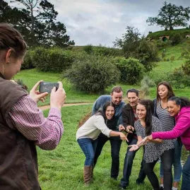 Guided tour group posing for a photo near a pond at Hobbiton Movie Set
