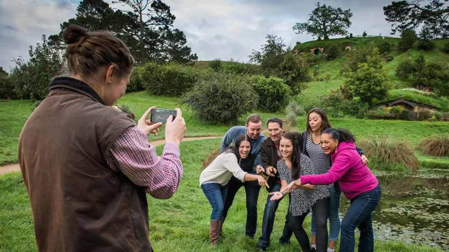 Guided tour group posing for a photo near a pond at Hobbiton Movie Set