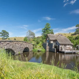 Stone bridge and watermill next to lake on the Hobbiton Movie Set tour