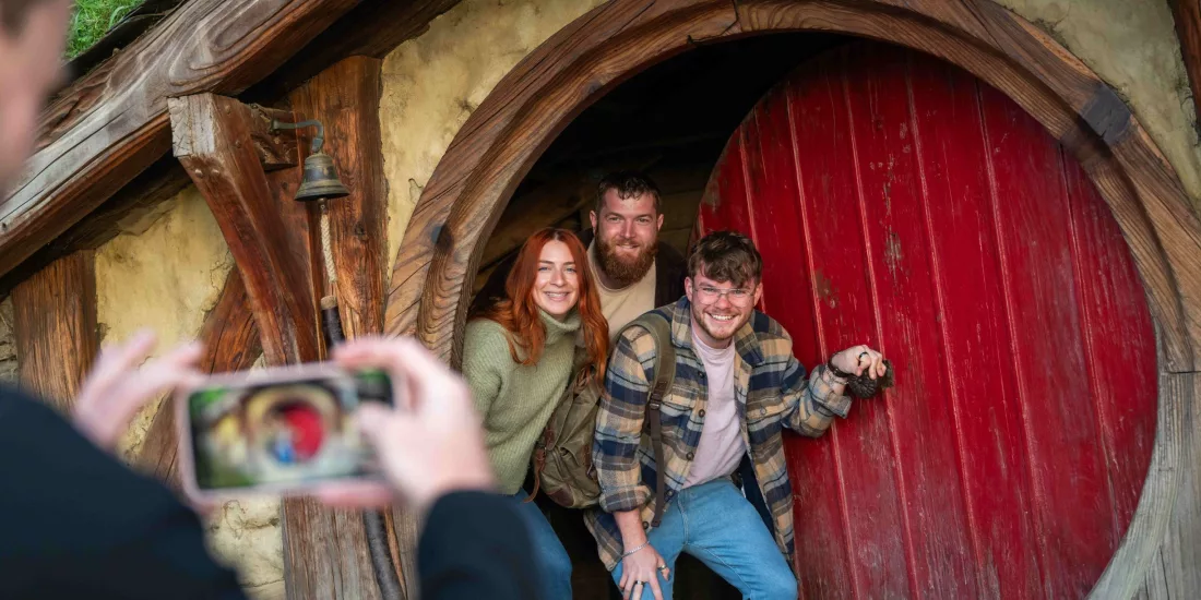 Group of friends smiling and posing in the doorway of a Hobbit Hole