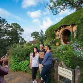 Visitors taking a photo outside Bag End with the famous round green Hobbit door