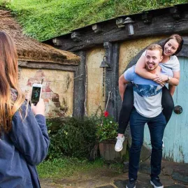 Couple posing for a photo outside a blue Hobbit door on the Hobbiton Movie Set tour