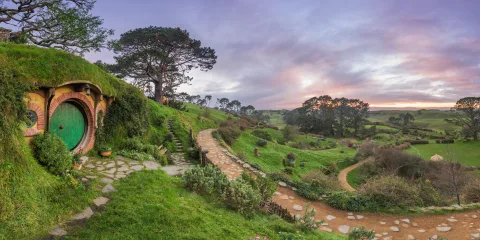 Bag End at the Hobbiton Movie Set in Matamata, with rolling green hills and pathways at sunrise in the Waikato region of New Zealand