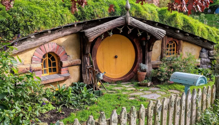 Hobbit house with a yellow round door, rustic garden, and wooden picket fence at the Hobbiton Movie Set