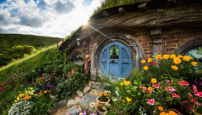 Hobbiton Movie Set hobbit hole with a round blue door surrounded by colourful flowers in Matamata New Zealand