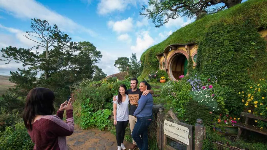 Visitors taking a photo outside Bag End with the famous round green Hobbit door