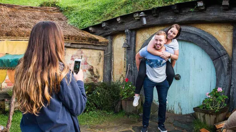 Couple posing for a photo outside a blue Hobbit door on the Hobbiton Movie Set tour