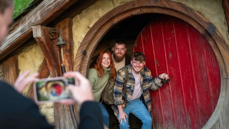 Group of friends smiling and posing in the doorway of a Hobbit Hole