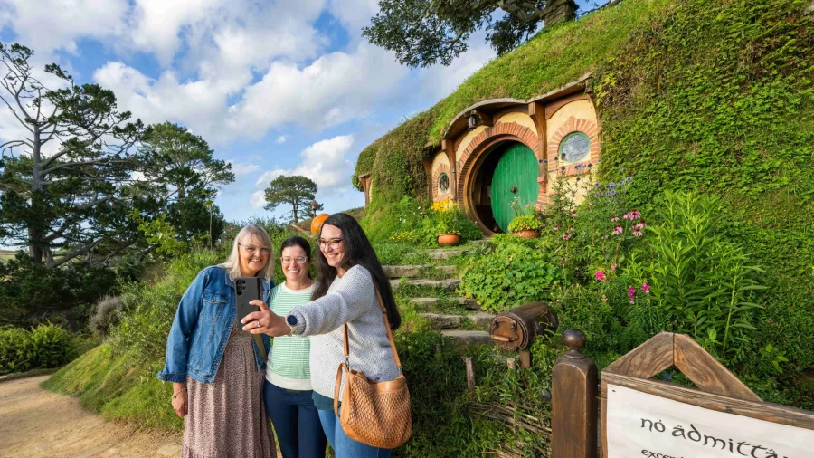 Group of women taking a selfie outside Bag End with the green round door
