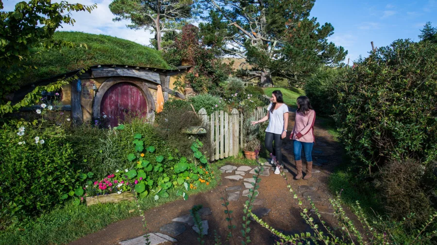 Scenic view of Hobbiton Movie Set with hobbit holes, green hills, and colourful gardens