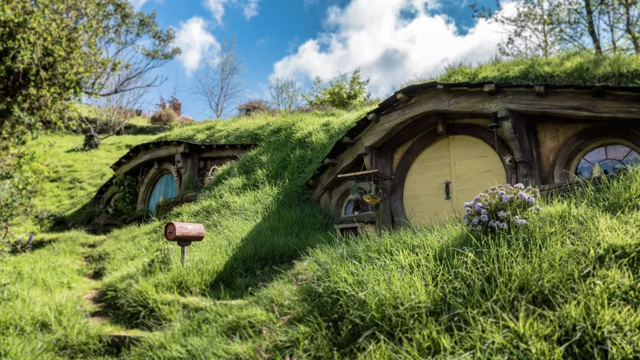 Hobbit holes with round doors and grassy rooftops at the Hobbiton Movie Set in Matamata, New Zealand, featured in The Lord of the Rings and The Hobbit films.
