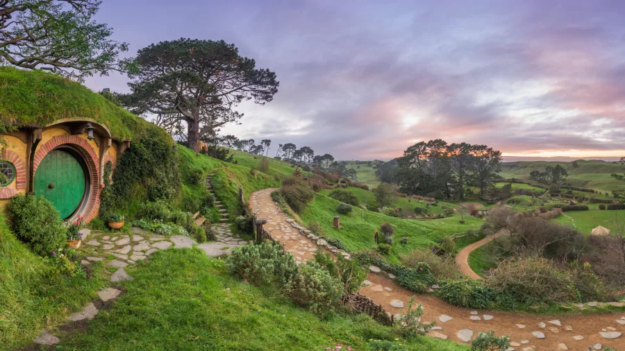 Bag End at the Hobbiton Movie Set in Matamata, with rolling green hills and pathways at sunrise in the Waikato region of New Zealand