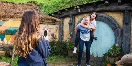 Couple posing for a photo outside a blue Hobbit door on the Hobbiton Movie Set tour