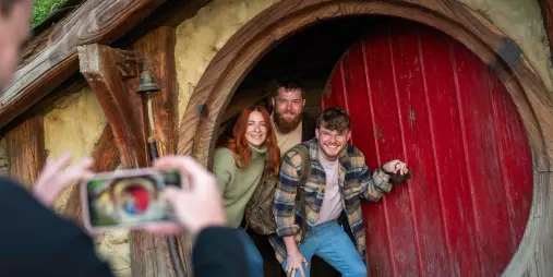 Group of friends smiling and posing in the doorway of a Hobbit Hole