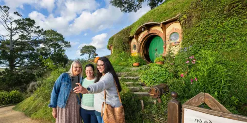 Group of women taking a selfie outside Bag End with the green round door