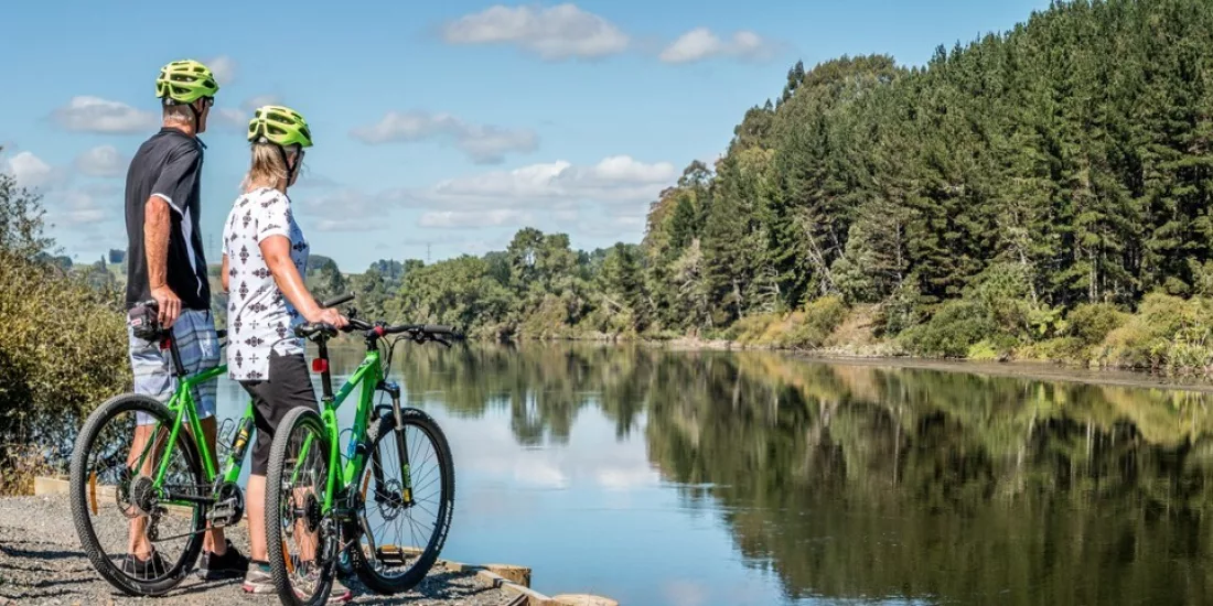 Couple on green bikes taking in the view along the Waikato River