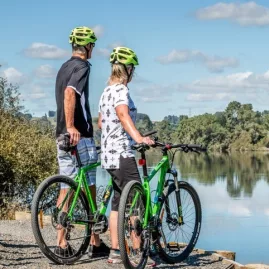 Couple on green bikes taking in the view along the Waikato River