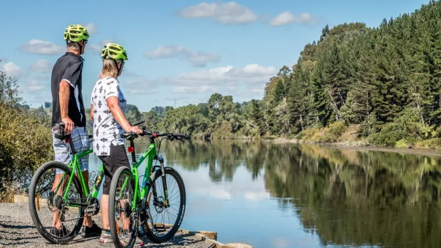 Couple on green bikes taking in the view along the Waikato River