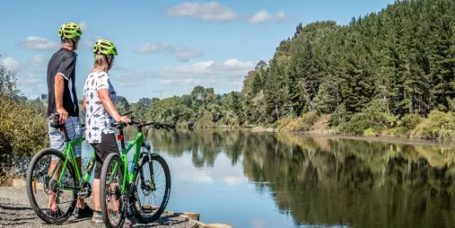 Couple on green bikes taking in the view along the Waikato River