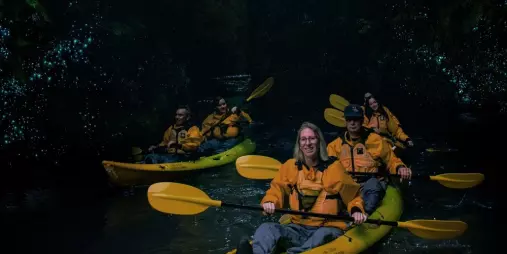Group kayaking through glowworm-lit canyon on a Full Day Private Adventure with Riverside Adventures