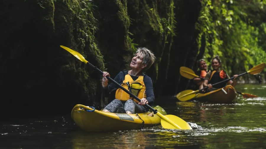 Woman kayaking solo through a narrow, lush gorge along the Waikato River