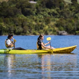 Two women kayaking on a clear lake with Riverside Adventures during a sunny day
