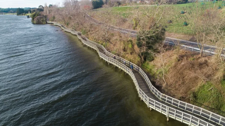 Aerial view of cyclists riding along a winding boardwalk by the lake on the Te Awa River Ride
