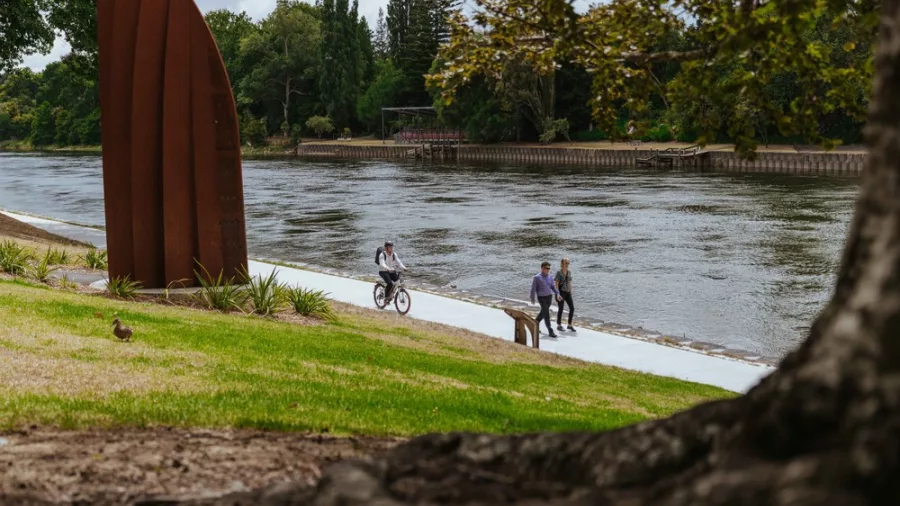 Cyclist and pedestrians on the riverside path between Hamilton Gardens and Ngāruawāhia