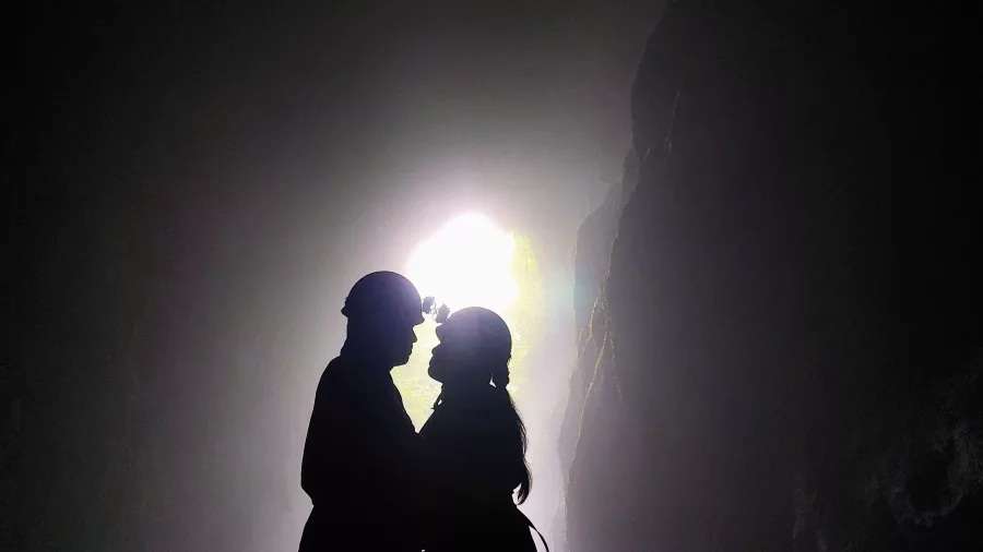 Caving couple silhouette with light shaft in Waitomo