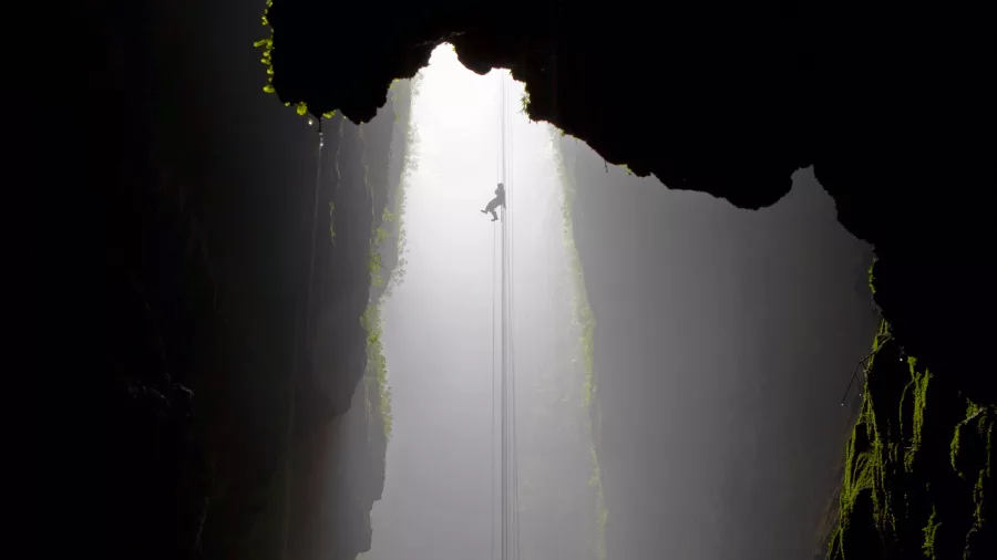 Abseiler descending into a mist-filled cave at Waitomo