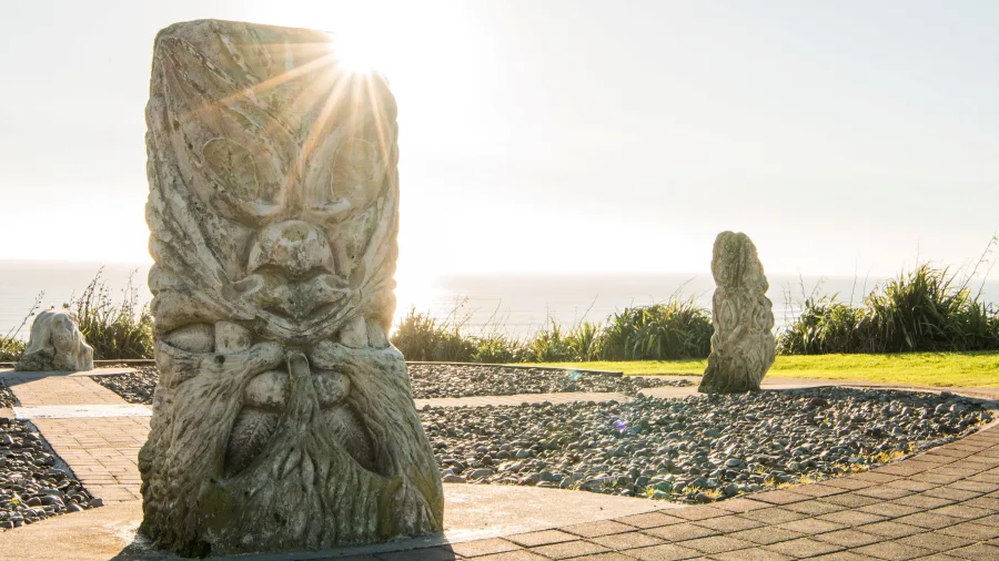Four Directions sculpture in Raglan, Waikato, New Zealand, with the sun shining over the ocean in the background.