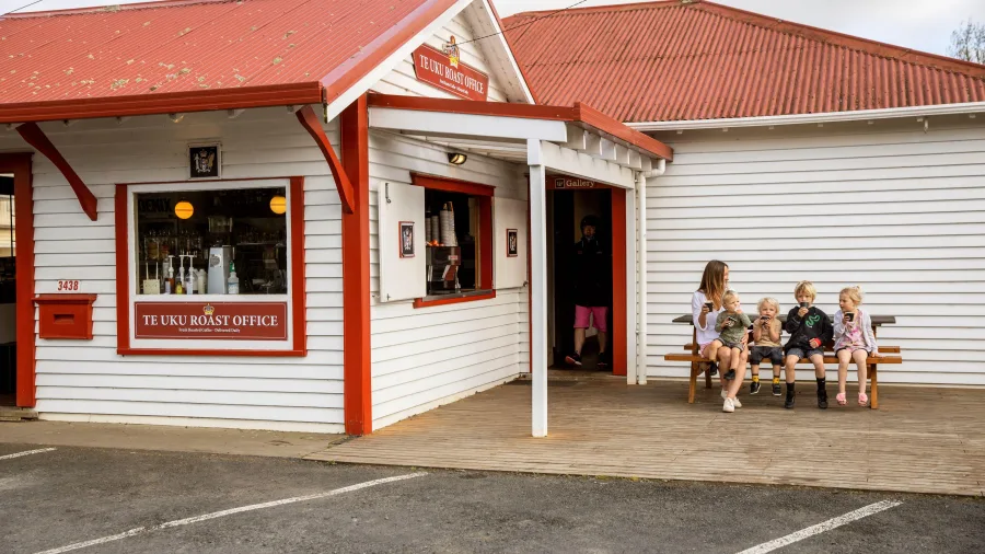 Family with children enjoying drinks outside Raglan Roast coffee in Waikato, New Zealand.