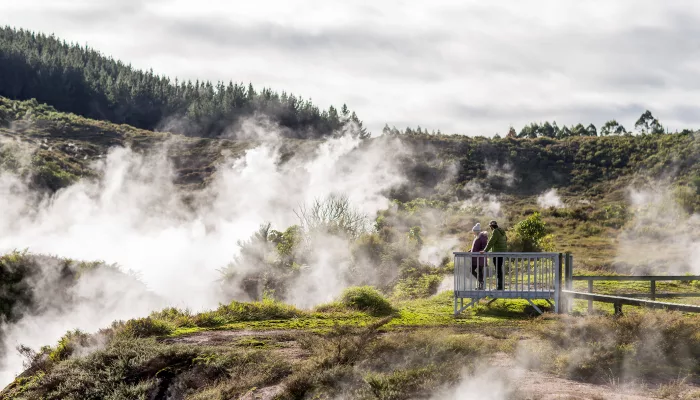 Visitors viewing steam vents from a boardwalk at Craters of the Moon geothermal area in Taupo, New Zealand.