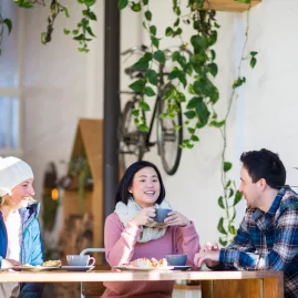 Friends enjoying coffee and pastries at The Storehouse café in Taupō, New Zealand, surrounded by lush indoor plants.