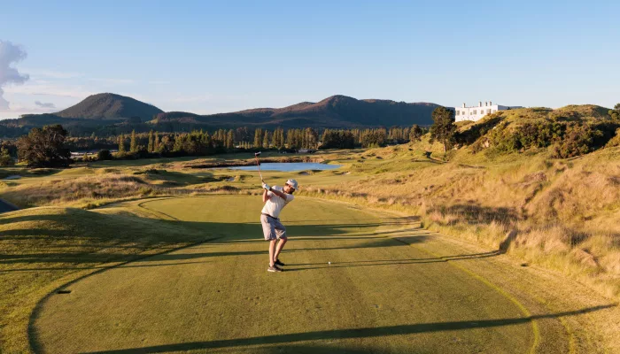 Golfer swinging on the fairway at Kinloch Golf Club’s Jack Nicklaus-designed championship course in Taupō, New Zealand.