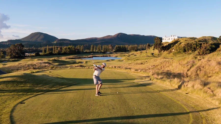 Golfer swinging on the fairway at Kinloch Golf Club’s Jack Nicklaus-designed championship course in Taupō, New Zealand.