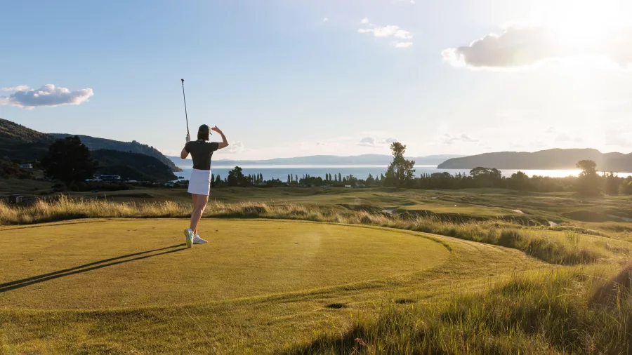 Golfer teeing off with stunning Lake Taupō views at Kinloch Golf Club’s Jack Nicklaus-designed championship course.
