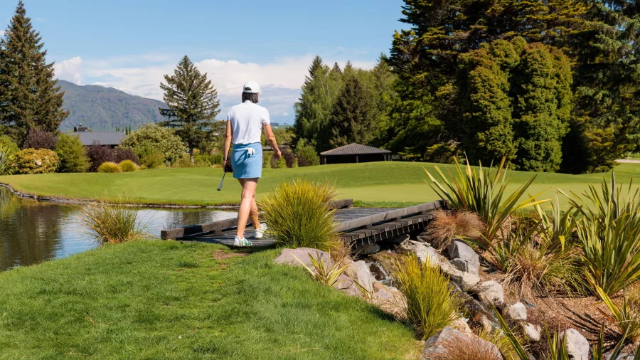 Golfer crossing a small bridge at Wairakei Golf Course and Wildlife Sanctuary in Taupō, New Zealand.