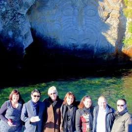 Group of tourists posing in front of the Māori Rock Carvings on Lake Taupō