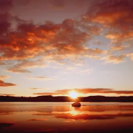 Sunset over Lake Taupō with a silhouetted boat in the distance
