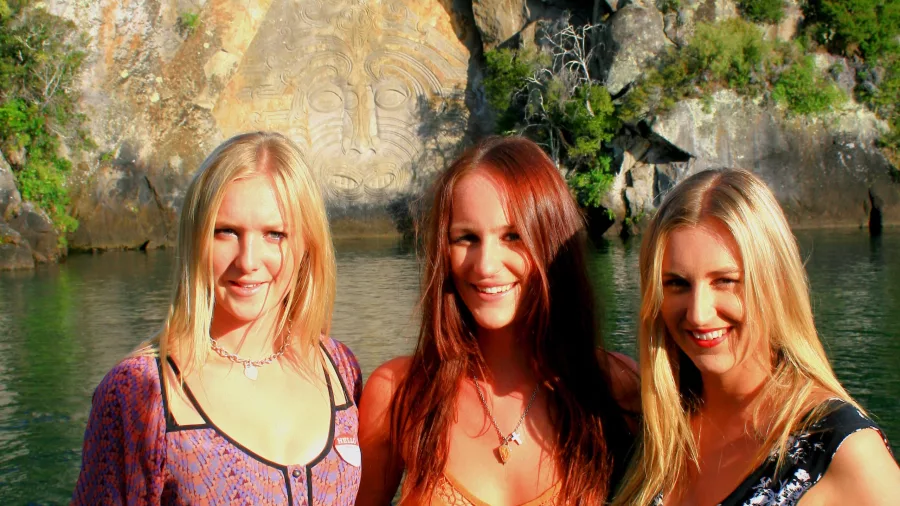 Group of friends smiling in front of the Ngātoroirangi Māori Rock Carvings