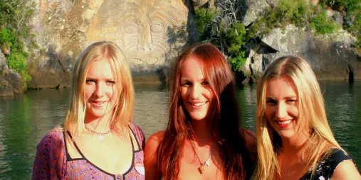 Group of friends smiling in front of the Ngātoroirangi Māori Rock Carvings