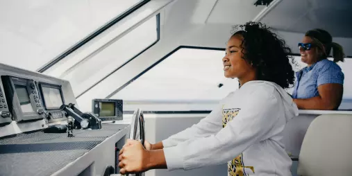 Child steering cruise boat on Lake Taupō with guide watching