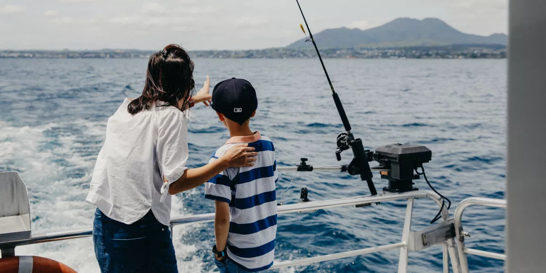 Mother and son fishing from the back of a charter boat on Lake Taupō