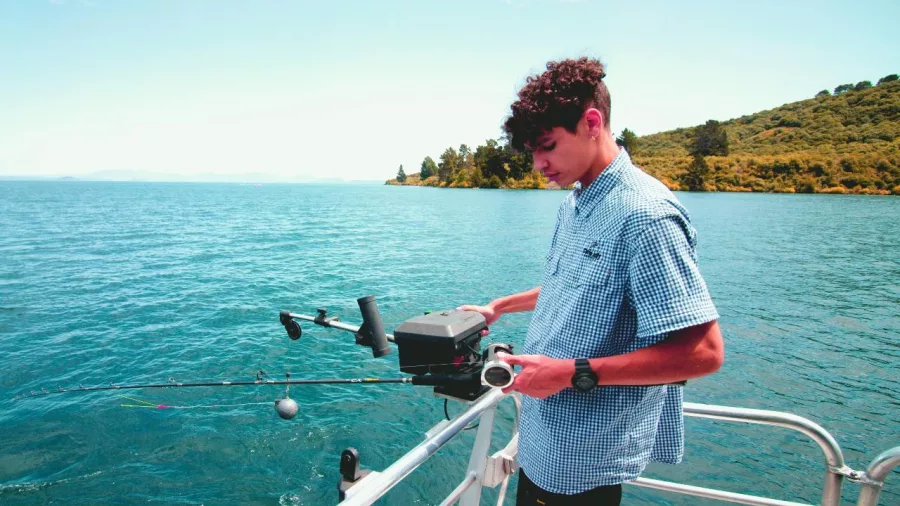 Teenage boy using a fishing rod on a Lake Taupō charter boat