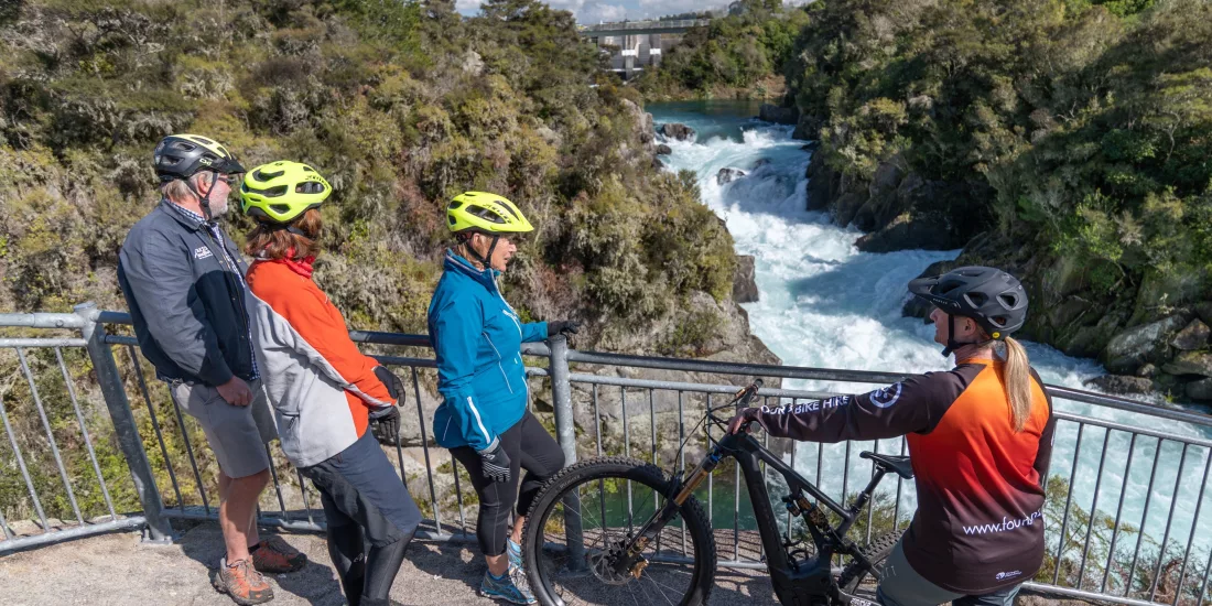 Group of cyclists stopping at a lookout point over Huka Falls while riding a scenic trail in Taupō, New Zealand.