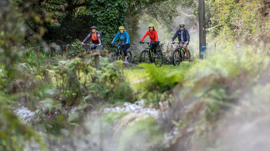 Group of cyclists riding through geothermal steam near Taupō
