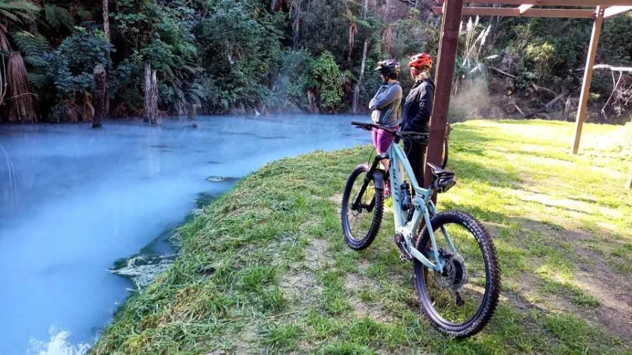 Two cyclists admiring the blue geothermal stream near Wairakei